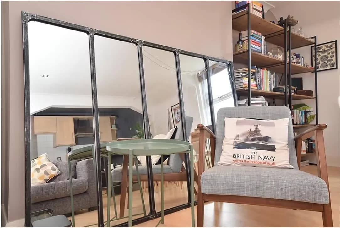 Living room with a black-framed mirrored screen and open shelving