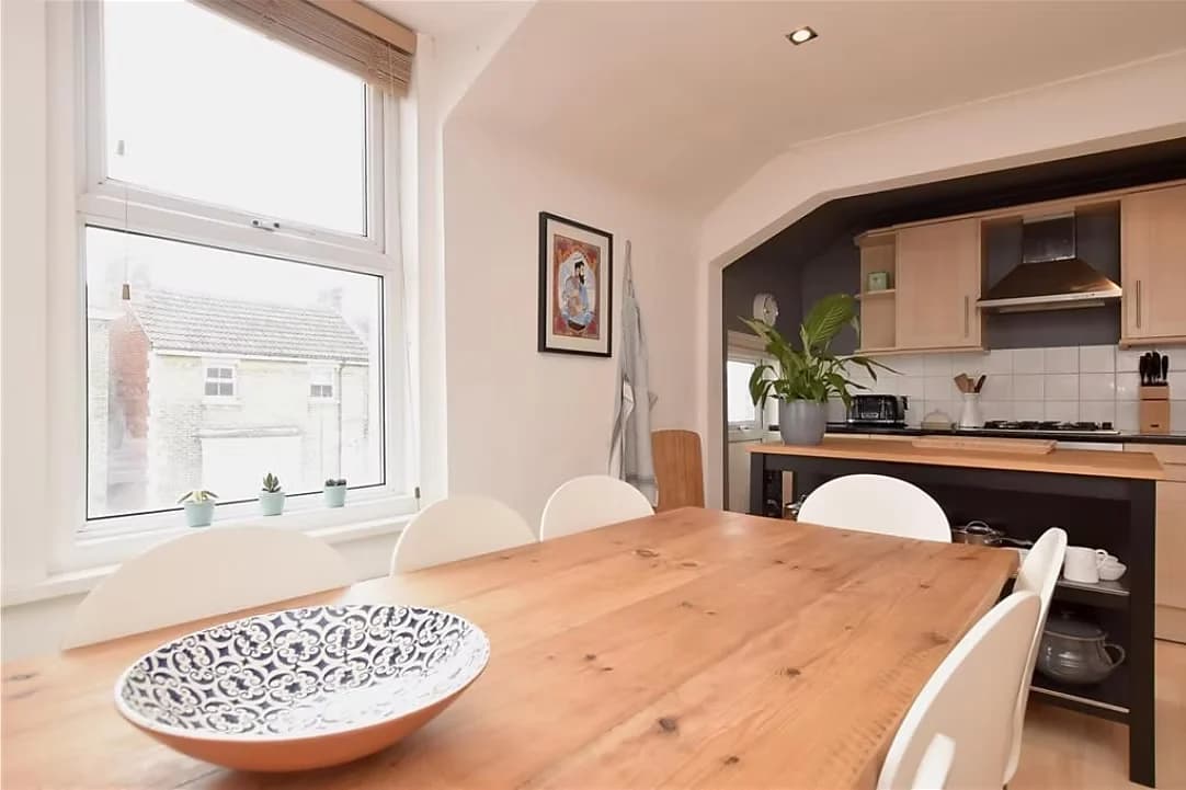 Kitchen and dining room with a timber table beneath a sash window