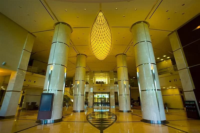 Double-height lobby with clad columns and a large illuminated woven pendant