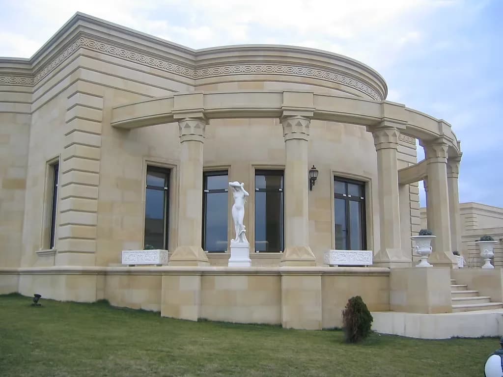 Curved colonnaded elevation in cut stone, a white statue standing between the columns