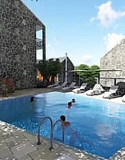 Outdoor swimming pool with sun loungers beside a stone-clad building