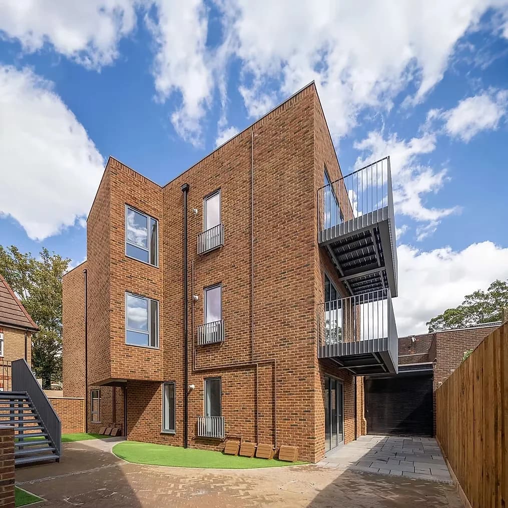The completed block from the rear courtyard, brick elevations with steel balconies against a blue sky