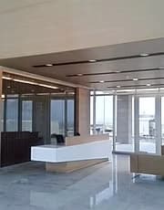 Minimal white reception desk in a glazed corporate lobby