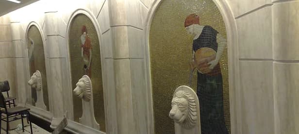 Stone bath interior with arched niches, mosaic figure panels and lion-head water spouts