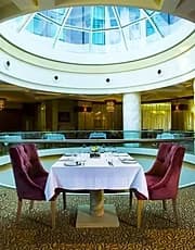 Formal hotel restaurant with laid tables beneath a large oval glazed dome
